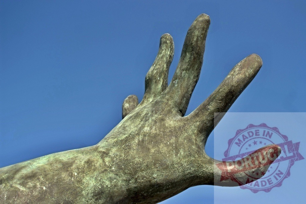 Bronze sculpture hand reaching against blue sky. Provincia de Castellon | Bronze statue hand with green patina reaching heavenward into a clear blue sky - Realisiert mit Pictrs.com