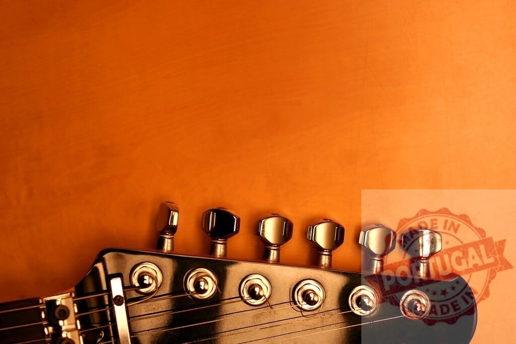 Electric guitar headstock resting on orange background | Headstock of electric guitar resting on orange background with copy space - Realisiert mit Pictrs.com