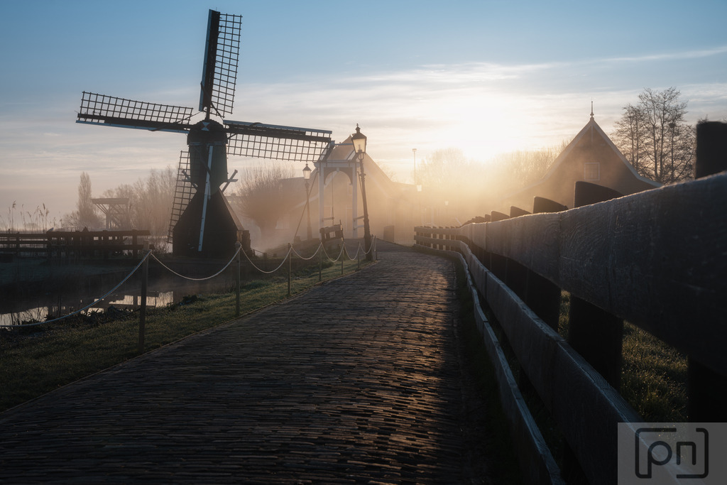 Zaandam | "Zaanse Schans Fotos" präsentieren eine zauberhafte Reise in die Vergangenheit der Niederlande. Die Zaanse Schans ist ein malerisches Dorf, das sich in der Nähe von Amsterdam befindet und als lebendiges Freilichtmuseum bekannt ist. Die Fotos zeigen die einzigartige Atmosphäre dieses historischen Ortes, der eine Fülle von traditionellen Windmühlen, Holzhäusern, Brücken und Kanälen umfasst.

Die Windmühlen sind zweifellos die Hauptattraktion der Zaanse Schans. Die Fotos fangen die majestätische Präsenz dieser Windmühlen ein, die einst das industrielle Herz der Region bildeten. Jede Mühle hat ihre eigene Geschichte und diente einst verschiedenen Zwecken wie dem Mahlen von Getreide, dem Sägen von Holz oder der Herstellung von Farben und Ölen.

Die Bilder zeigen auch die charakteristischen grünen Holzhäuser, die typisch für die niederländische Architektur sind und eine gemütliche und idyllische Atmosphäre schaffen. Die Schönheit der Zaanse Schans wird durch die Spiegelungen der Häuser in den Kanälen verstärkt, die eine malerische Kulisse für die Fotografien bieten.

Die Fotos erfassen die Traditionen und das Handwerk der Vergangenheit, die in der Zaanse Schans lebendig gehalten werden. Besucher haben die Möglichkeit, Handwerker bei der Arbeit zu beobachten und alte Techniken wie das Herstellen von Holzschuhen, Käse und Schokolade zu erleben.

Inmitten dieser charmanten Kulisse fangen die Fotos das Gefühl von Ruhe und Nostalgie ein, das die Zaanse Schans so besonders macht. Es ist eine Zeitreise in die niederländische Geschichte und Kultur, die Besucher und Betrachter gleichermaßen verzaubert und inspiriert.

Ob Sie von der Erkundung historischer Stätten fasziniert sind oder einfach nur die Schönheit und den Charme der Zaanse Schans bewundern möchten, diese Fotos bieten einen unvergesslichen Einblick in diese einzigartige Perle der niederländischen Landschaft