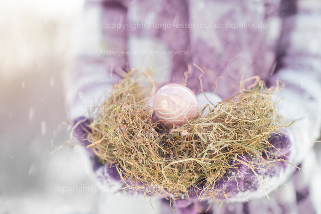 Easter in the snow | Eine Frau trägt ein Osternest. Sie trägt Wollkleidung und trägt Handschuhe. Es schneit zu Ostern. Copy Space.