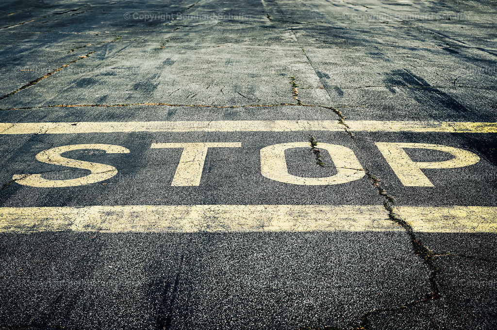 "Stop!" | Die Aufschrift „Stop“ auf einer Asphaltstraße.  - Realisiert mit Pictrs.com
