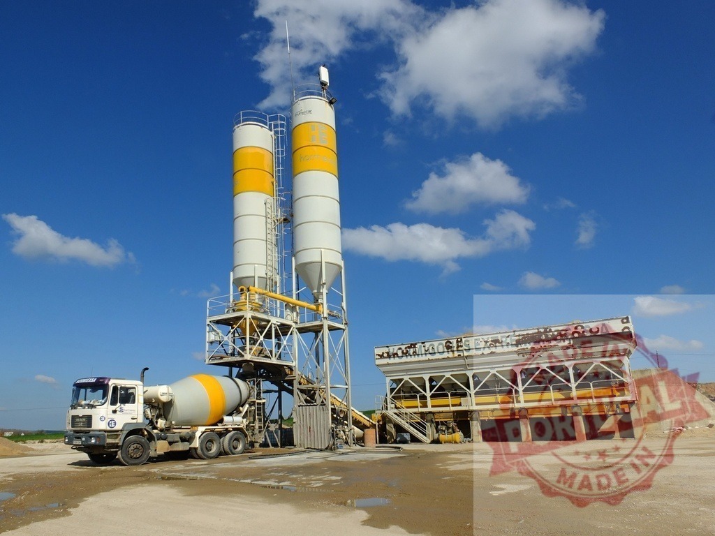 Concrete plant mixing station with mixer truck loading | Concrete mixing plant and delivery truck operating under a clear blue sky - Realized with Pictrs.com