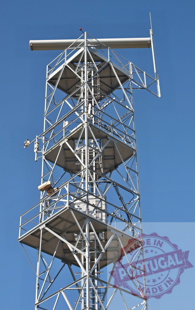 Telecommunication tower with antennas and radar is standing against blue sky | Metal telecommunication tower with antennas and radar is standing against blue sky on sunny day - Realized with Pictrs.com