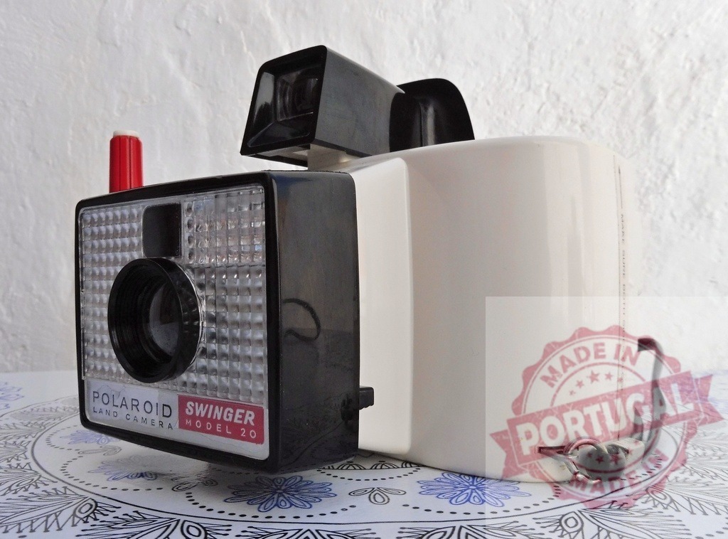 Polaroid Swinger Model 20 instant camera vintage photography | Vintage Polaroid Swinger Model 20 instant camera sitting on a patterned surface - Realized with Pictrs.com