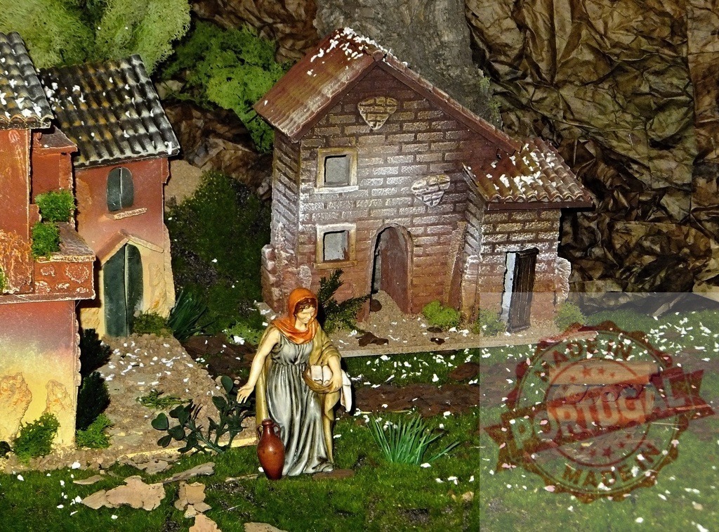 Woman carrying water and bread in a nativity scene village | Figurine of a woman carrying water and bread in a nativity scene village, with houses and plants - Realized with Pictrs.com