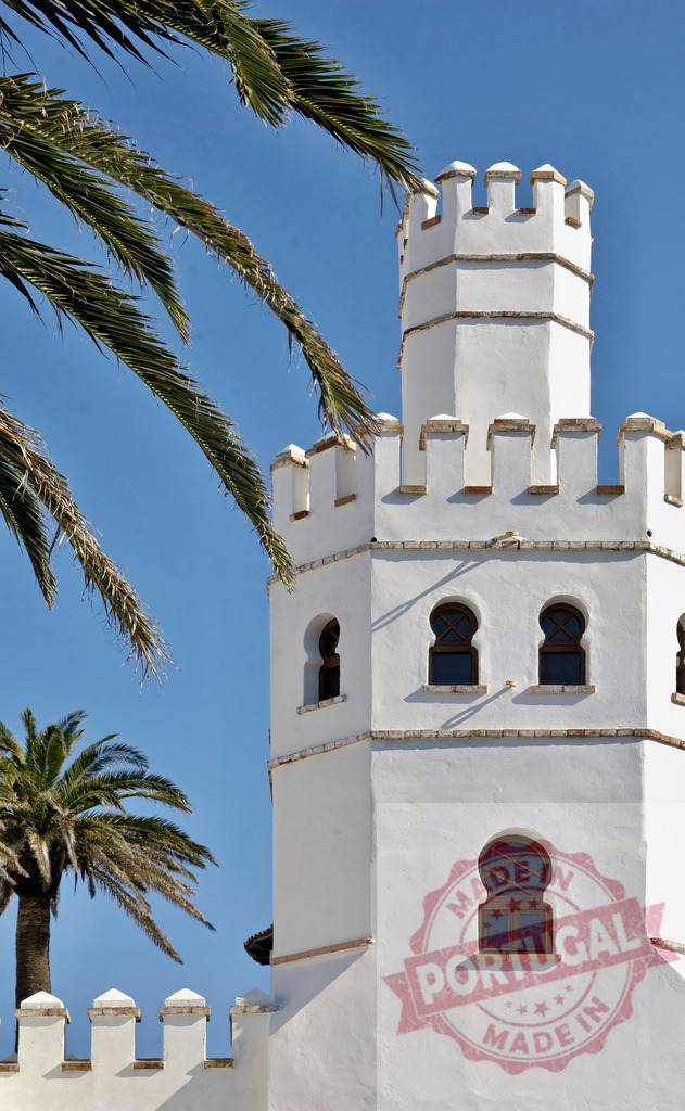 Palacio de Acebron tower, Doñana National Park, Huelva architecture details. Espana - Cadiz | White tower with battlements and Moorish windows under a clear blue sky, framed by palm fronds - Realisiert mit Pictrs.com