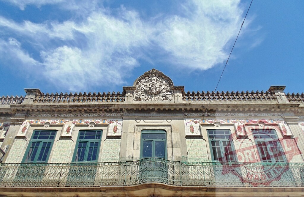 Aveiro Region - Portugal Architectural details of traditional Portuguese urban building | Old building facade featuring azulejo tiles, balconies, and decorative crest under blue sky - Realized with Pictrs.com