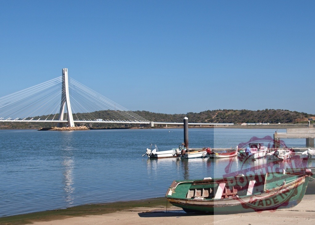 Guadiana International Bridge spanning border of Portugal Spain | Guadiana International Bridge crossing the river with boats docked in the foreground - Realisiert mit Pictrs.com