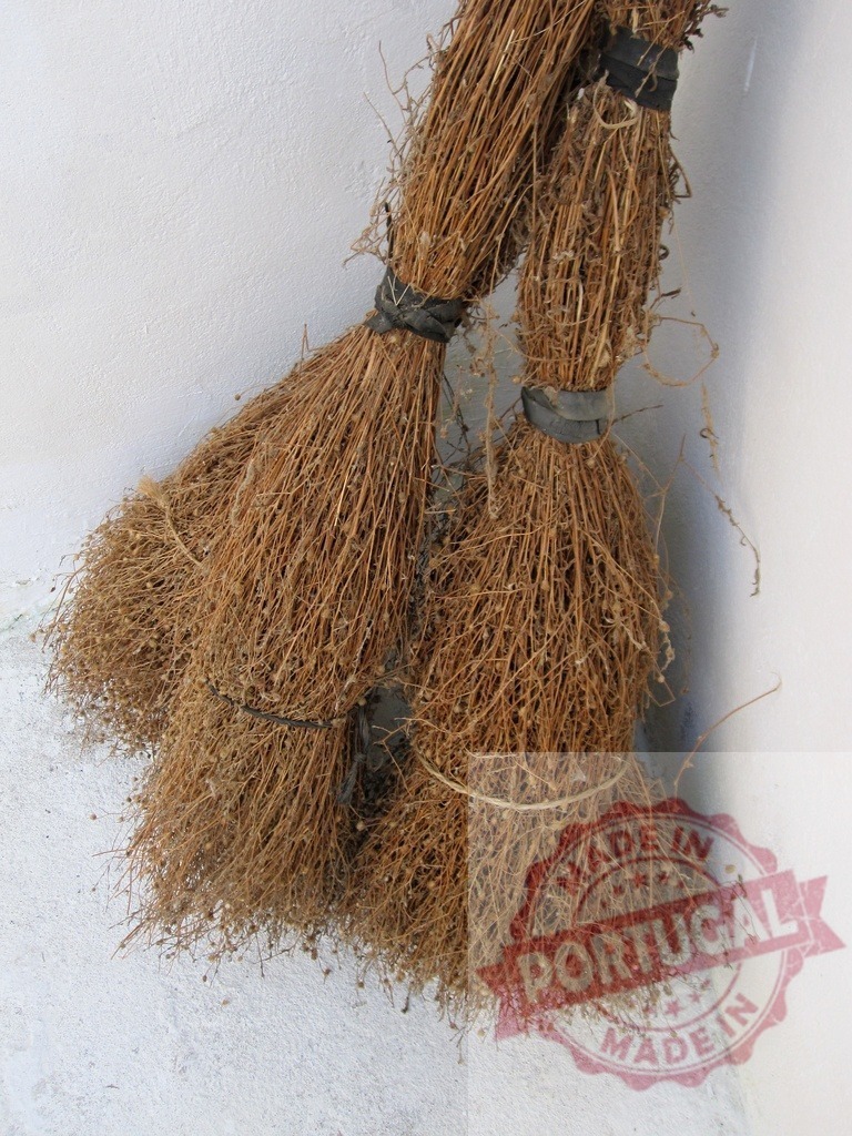 Traditional brooms hanging on a rustic wall corner | Dried plant brooms tied with black bands hanging against a white textured wall - Realisiert mit Pictrs.com