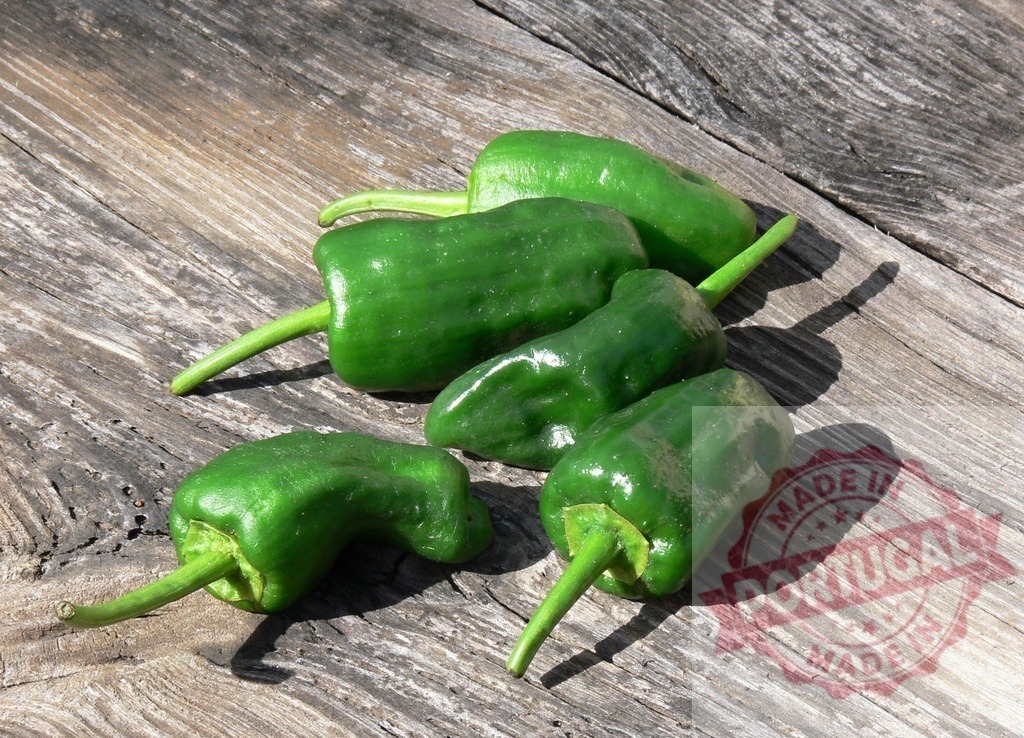 Fresh Padrón peppers on rustic wooden table | Padrón peppers resting on a vintage wooden surface in natural light - Realized with Pictrs.com