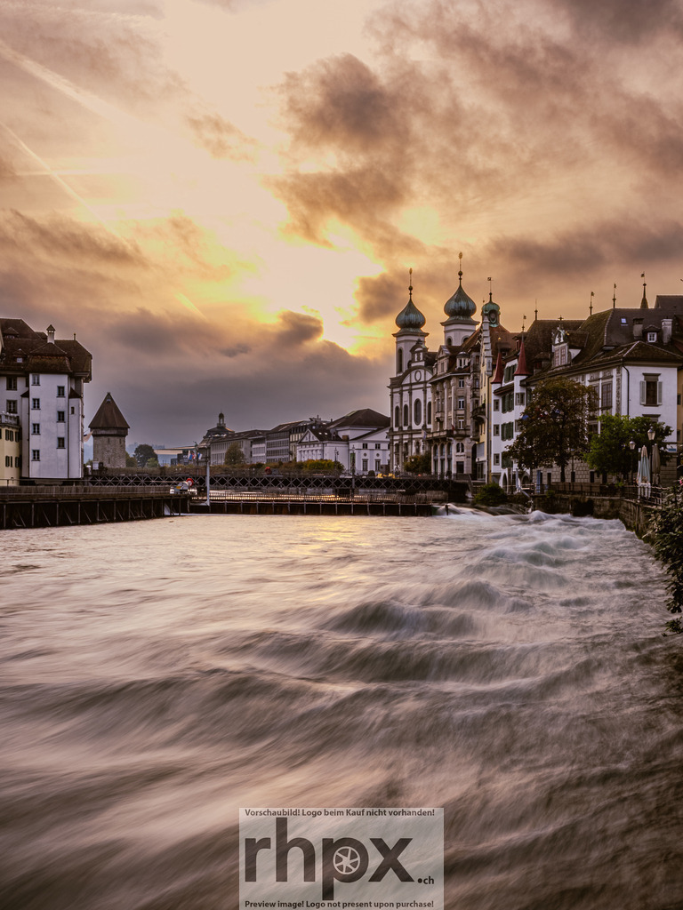 Nadelwehr und Jesuitenkirche | <p><strong>Strömung. Wolken. Baukunst.</strong></p><p>Die Reuss zieht als seidiges Band durch das Herz von Luzern, eingefangen in einer dynamischen Langzeitbelichtung. Unter einem dramatischen Wolkenhimmel bilden das historische Nadelwehr und die barocke Jesuitenkirche eine unverwechselbare Kulisse voller Kraft und Eleganz.</p><p>Wähle unter "Produktauswahl" dein Wunschformat: Vom klassischen Wandbild über Puzzle & Tassen bis zum digitalen Download (z.B. als Handy-Hintergrund).</p> - Realisiert mit Pictrs.com