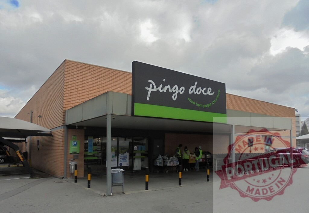 Pingo Doce supermarket facade in Portugal with shopping carts | Pingo Doce retail grocery store exterior with shoppers and a cloudy sky - Realized with Pictrs.com