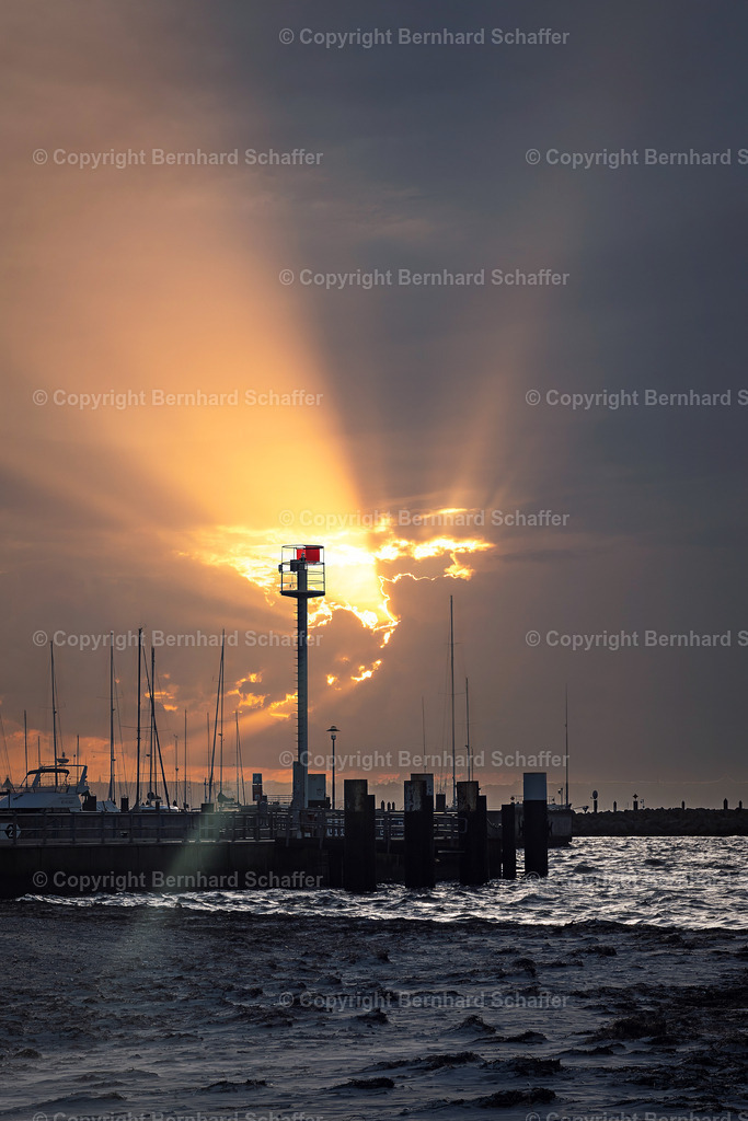 Sonnenstrahlen über Fähranlieger | Ein Sandstrand an der Kieler Förde und ein Steg mit Sonnenstrahlen, die nach einem Gewitter durch die Wolken brechen. - Realisiert mit Pictrs.com