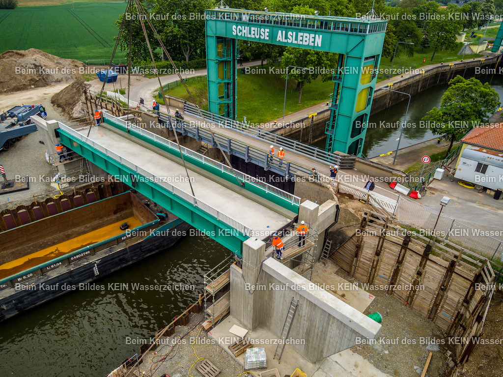 Schleuse_Alsleben_Foto_Lehmann-42 | Die Drohnenaufnahme zeigt die neu eingesetzte Brücke an der Schleuse Alsleben aus nächster Nähe. Das Brückenbauwerk liegt bereits auf den vorgesehenen Lagern auf, während Monteure letzte Justierungsarbeiten durchführen. Die Detailaufnahme vermittelt einen unmittelbaren Eindruck von der Präzision, mit der das schwere Bauteil während des Einbaus ausgerichtet werden muss.Die Aufnahme ist Teil des Mitteldeutschen Bildarchivs von Luftbildfotograf Steffen Lehmann. - Realisiert mit Pictrs.com