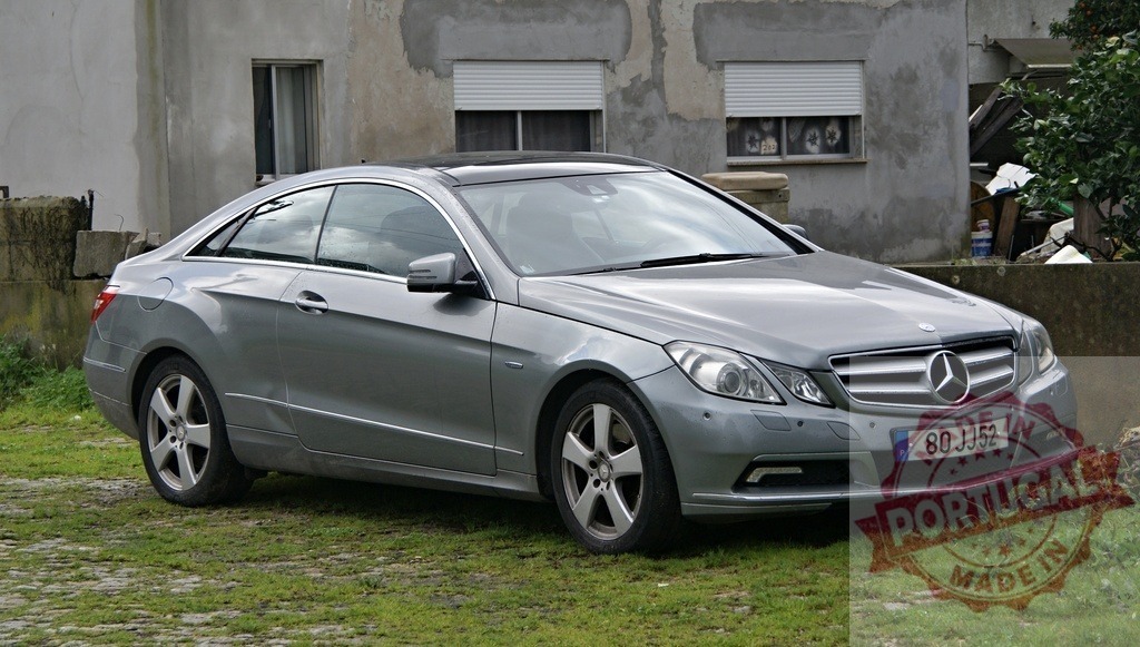Mercedes-Benz E-Klasse coupe parked on green grass | Silver Mercedes-Benz E-Klasse coupe parked outdoors on a grassy patch in front of a building - Realisiert mit Pictrs.com