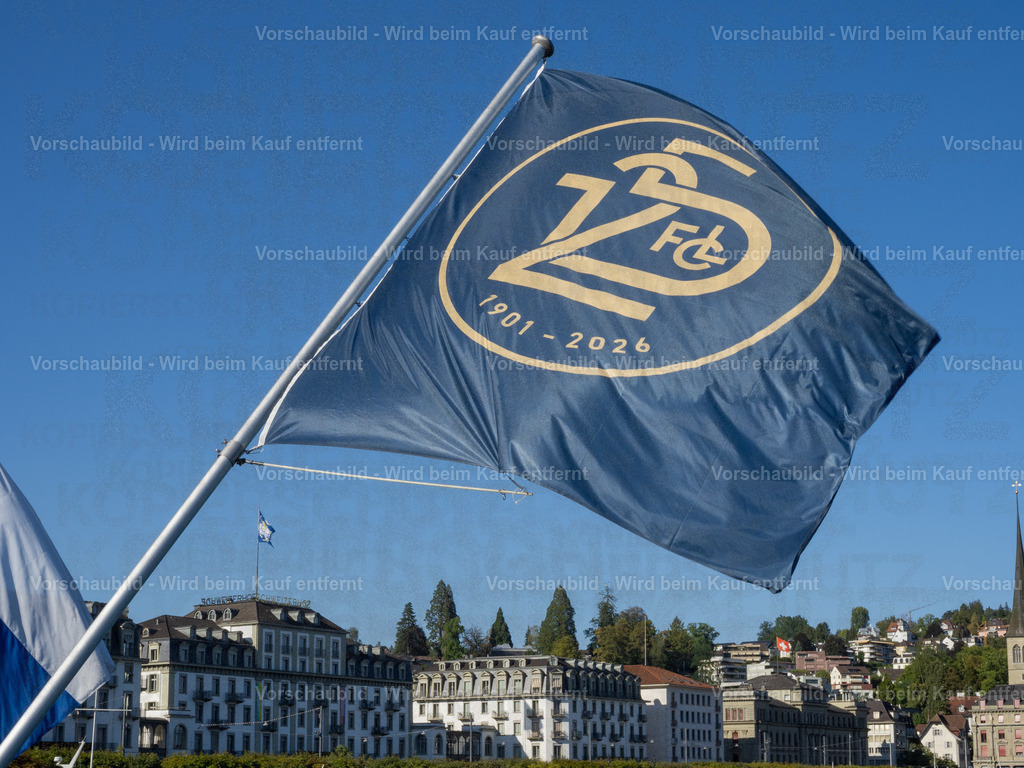 125 Jahre FCL – Luzern in Blau-Weiss | Die blau-weissen Fahnen wehen an der Seebrücke im Wind und zelebrieren das 125-Jahre-Jubiläum des FC Luzern. Dahinter erstreckt sich die Kulisse der Luzerner Seepromenade mit dem traditionsreichen Hotel Schweizerhof. - Realisiert mit Pictrs.com