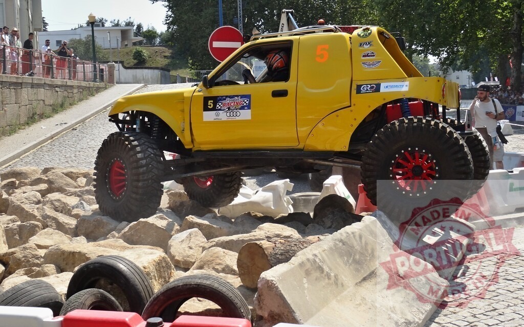 Yellow offroad vehicle climbing rocks during a competition | Modified offroad vehicle climbing rocks during an extreme 4x4 competition - Realisiert mit Pictrs.com