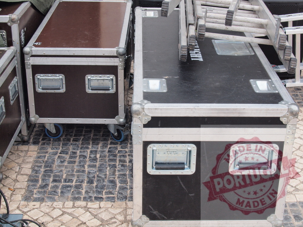 Flight cases and aluminum ladders lying on cobblestone pavement | Aluminum ladders resting on professional flight cases on a cobblestone pavement during an outdoor event setup - Realisiert mit Pictrs.com