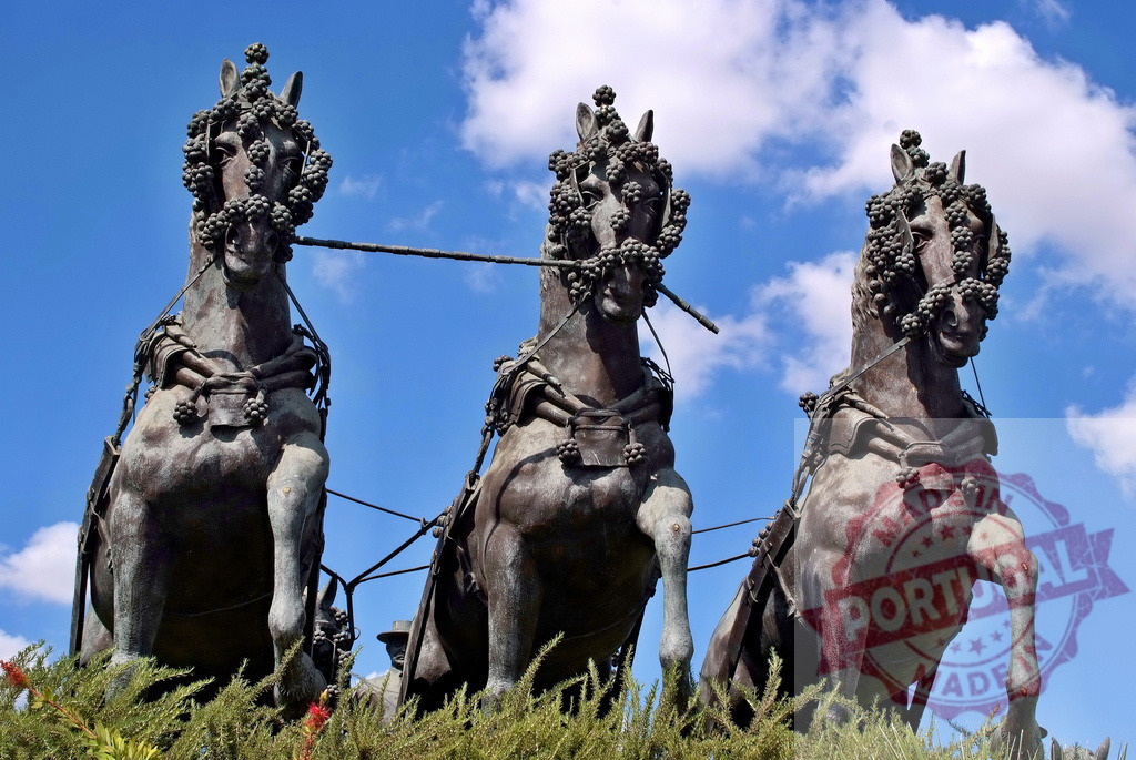 Three bronze horses featuring grape wreath decorations under blue sky. Espana - Cadiz | Bronze horse statues with grape wreaths against a bright blue sky and white clouds - Realized with Pictrs.com