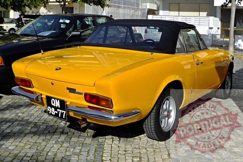 Yellow Fiat 124 Sport Spider parked on cobblestone street | Classic yellow Fiat 124 Sport Spider parked on a cobblestone street, showcasing its vintage charm and design - Realized with Pictrs.com