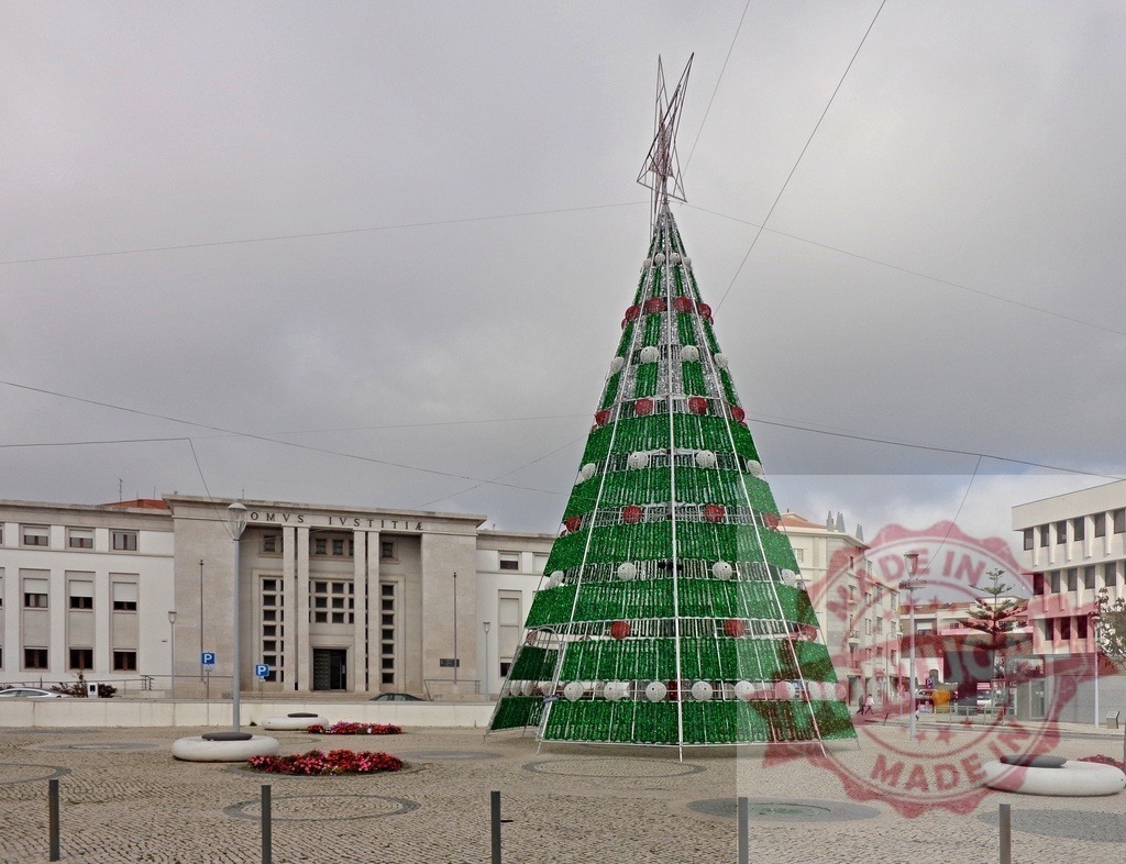 Large christmas tree standing in a square in front of a courthouse | Green and red christmas tree standing in a paved square with a courthouse in the background - Realisiert mit Pictrs.com