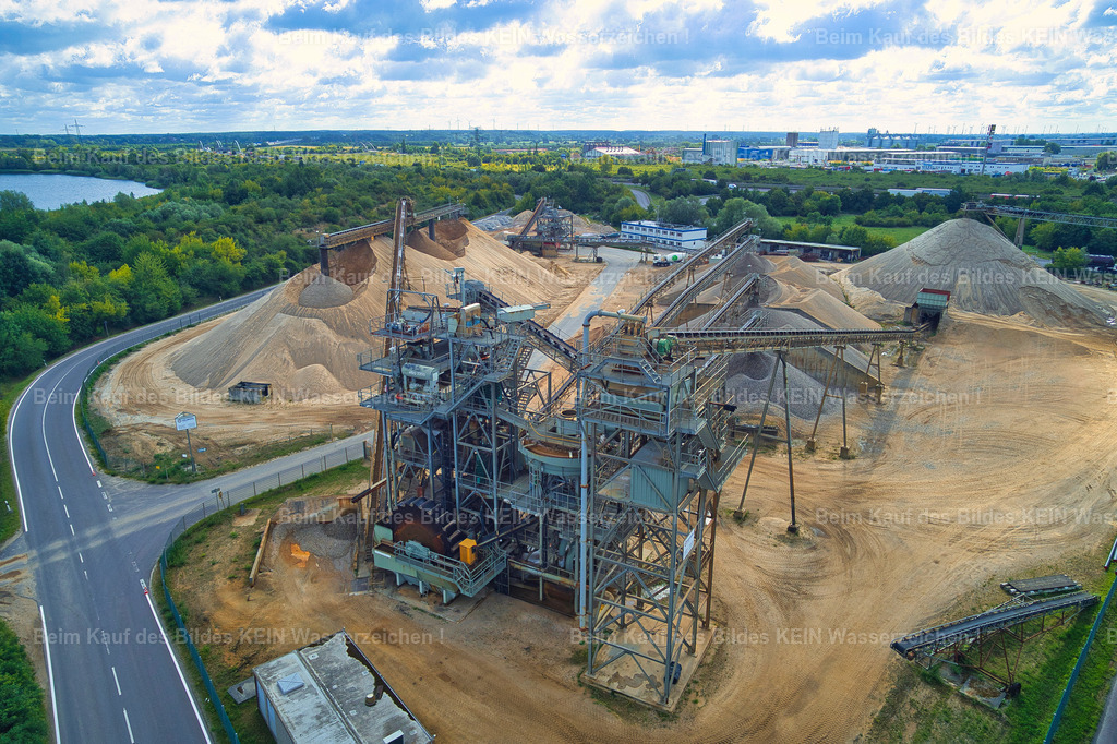 hülskens_1_0037_GEN | Blick aus der Drohneperspektive auf das Kieswerk Rothensee in Magdeburg. Die nahe Perspektive richtet den Blick unmittelbar auf die Förderbänder, Sandflächen und technischen Anlagen des Kieswerks.Im Gegensatz zur vorherigen großräumigen Tragschrauberaufnahme steht hier nicht die Dimension des gesamten Betriebsgeländes im Mittelpunkt, sondern die technische Struktur des Standortes. Förderanlagen, Materialflächen und Sand bilden ein prägnantes industrielles Motiv.Die Aufnahme ist Teil der umfassenden Dokumentation des Kieswerks. Neben den weiträumigen Luftbildern entstanden auch solche detailreichen Drohnenaufnahmen sowie Fotografien direkt vom Betriebsgelände.So ergänzen sich Übersicht und Detail: Während die Tragschrauberaufnahme die Größe und Lage des Kieswerks zeigt, macht die Drohnenperspektive die Arbeitsbereiche und technischen Einrichtungen aus unmittelbarer Nähe sichtbar. - Realisiert mit Pictrs.com