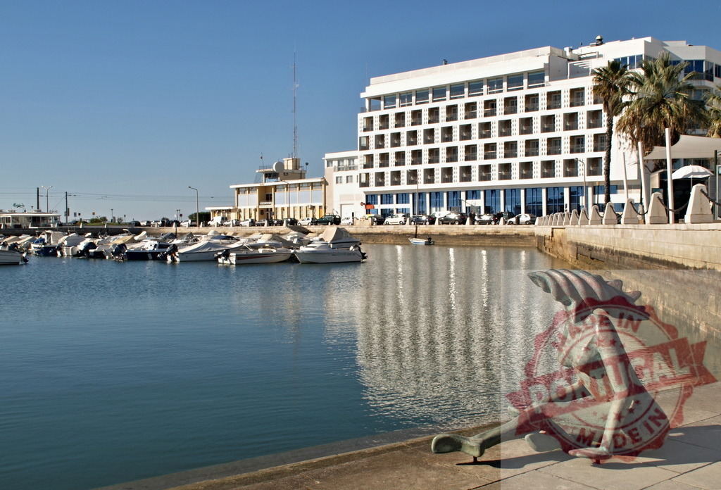 Bronze mermaid sculpture sitting along Cascais marina waterfront | Bronze mermaid sculpture overlooking marina with boats and hotel in Cascais, Portugal - Realized with Pictrs.com