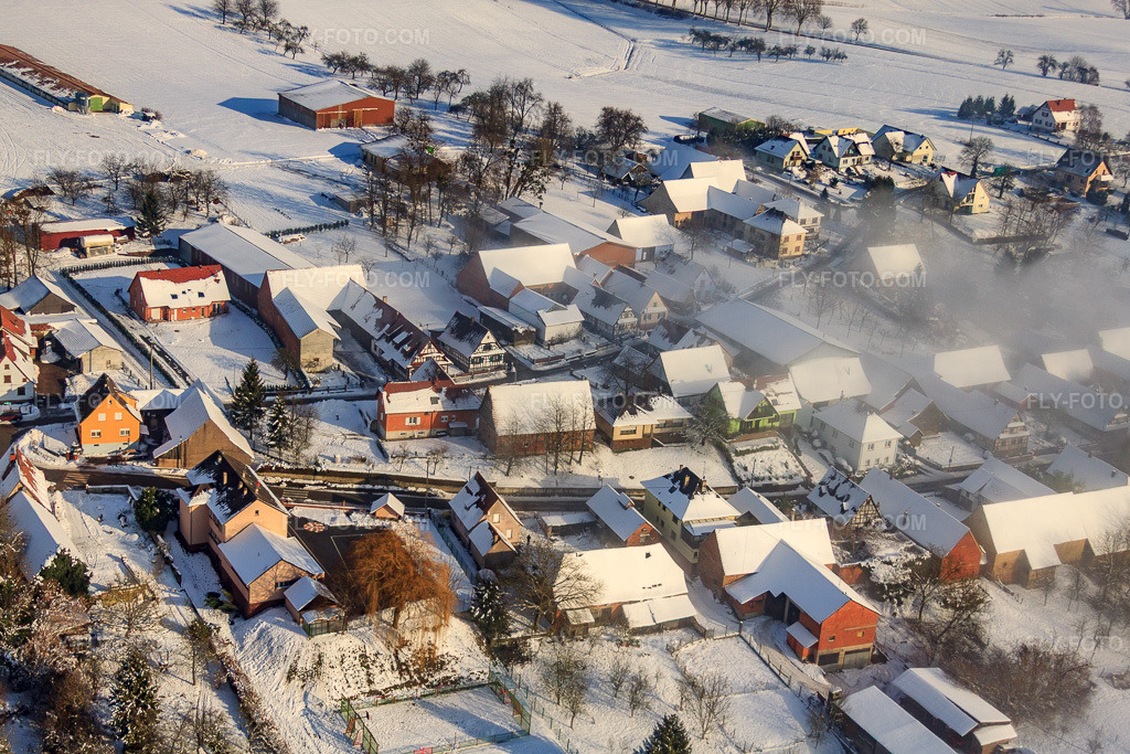 Aerial view: Rue du Laboureur in winter, with snow and clouds from the east in Wintzenbach in the state Bas-Rhin, France. – Photo: IMG_36204.jpg taken on 01/02/2011 by Werner Riehm/FLY-FOTO.com – Resolution of the original: 4752 x 3168 px
