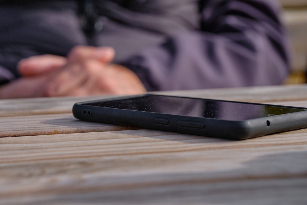 Älterer Mann mit einem Handy auf dem Holztisch | Wien, Austria - October 16, 2025: Älterer Mann mit einem Handy auf dem Holztisch. - Realisiert mit Pictrs.com