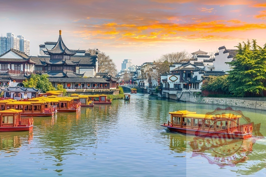 Nanjing Qinhuai River historic architecture with traditional boats at sunset | Traditional Chinese boats cruising on Qinhuai River with ancient buildings and a vibrant sunset sky - Realized with Pictrs.com