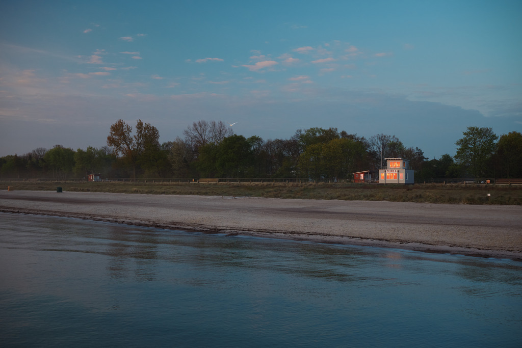 CS-240427-0854-1 | In den Fenstern der DLRG Wache am Strandaufgang 6 in der Boltenhagener Bucht an der Ostsee spiegelt sich der Sonnenaufgang