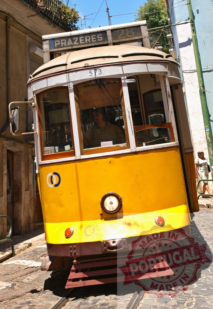 Yellow Lisbon Tram Ascending Prazeres District on Sunny Day | Vintage yellow tram climbing steep hill in historic Lisbon neighborhood, offering nostalgic glimpse into city's transportation - Realized with Pictrs.com