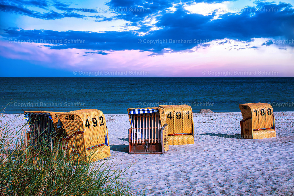 Strandkörbe im Abendlicht | Mehrere Strandkörbe und Dünengras am Sandstrand der Ostsee in abendlichem violettem Stimmungslicht.  - Realisiert mit Pictrs.com