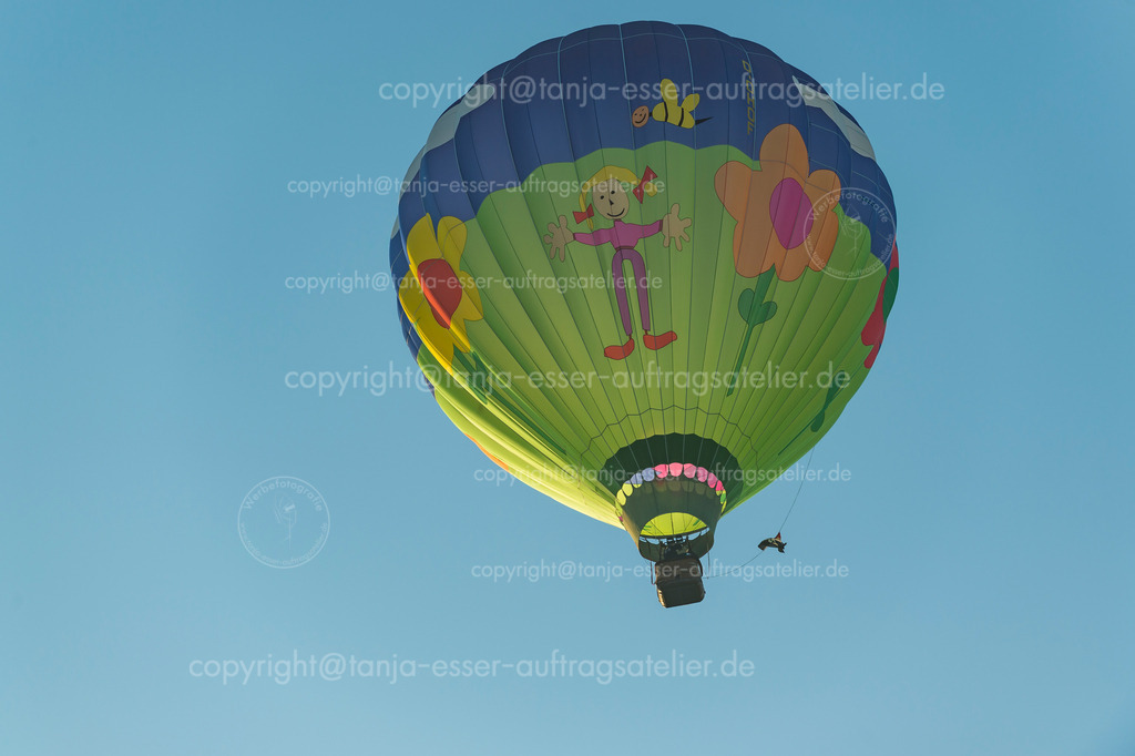 Bunter Heißluftballon mit Kindermotiv fliegt zur Sonne auf der WIM | Heißluftballon direkt von unten fotografiert in Oeventrop / Arnsberg am Morgen. Die Warsteiner Internationale Montgolfiade ist der Veranstalter.