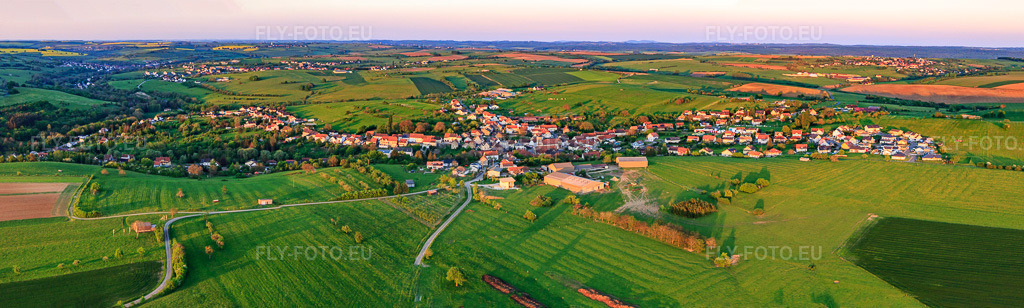 Vue aérienne: Panorama de la ville vue de l'ouest en soirée à Kalhausen dans le département Moselle, France. Photo: IMG_145898-Pano.jpg prise le 30/04/2025 par Werner Riehm/FLY-FOTO.eu – Résolution de l'original: 13106 x 3943 px