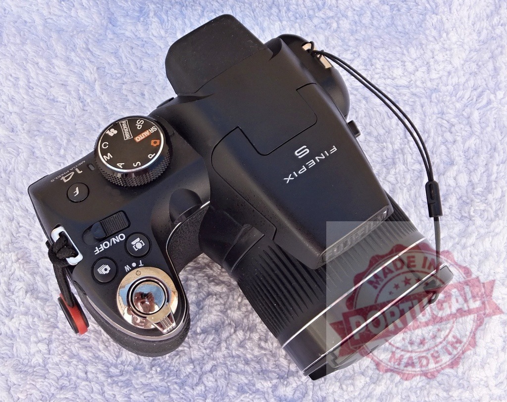 Fujifilm FinePix S digital bridge camera on white background | Black Fujifilm FinePix S bridge camera sitting on a white textured surface - Realisiert mit Pictrs.com