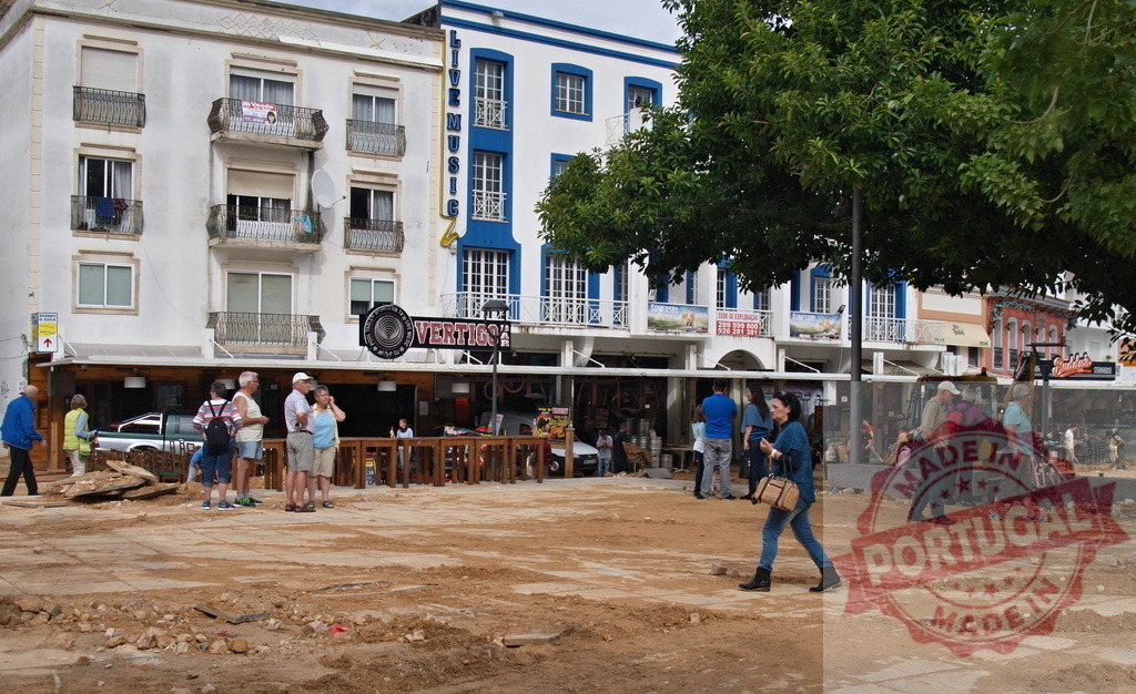 Urban square undergoing construction in Portugal with people | Albufeira Flood - discruction by weather problems People walking on a torn-up town square in a Portuguese city with buildings and cafes - Realisiert mit Pictrs.com