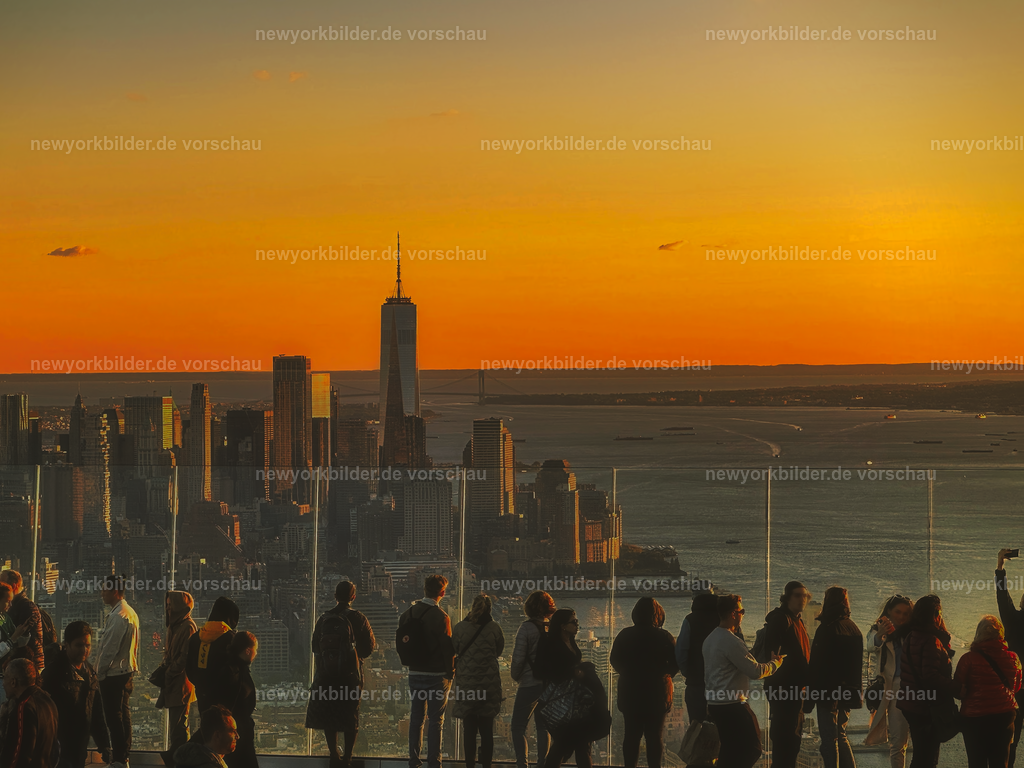 Sunset auf The Edge – Atemberaubender Blick bis nach Downtown Manhattan und dem One World Trade Center | Es gibt Momente in New York, die man nie vergisst – und der Sonnenuntergang auf The Edge gehört dazu. Hoch über den Straßen der Stadt, an der frischen Luft, stehen Menschen vor den gläsernen Wänden und bestaunen den Blick, der sich bis nach Downtown Manhattan und zum One World Trade Center erstreckt. Während die Sonne langsam untergeht, taucht ein tiefes Orange die Skyline in ein magisches Licht. Die Wolkenkratzer glühen, die Stadt wirkt wie ein lebendiges Kunstwerk. Dieser Augenblick ist mehr als ein Foto – er ist ein Erlebnis, das die Seele berührt. Für Fotografen, Reisende und alle, die New York lieben, ist The Edge der perfekte Ort, um den Tag ausklingen zu lassen und die Schönheit der Metropole in ihrer reinsten Form zu genießen