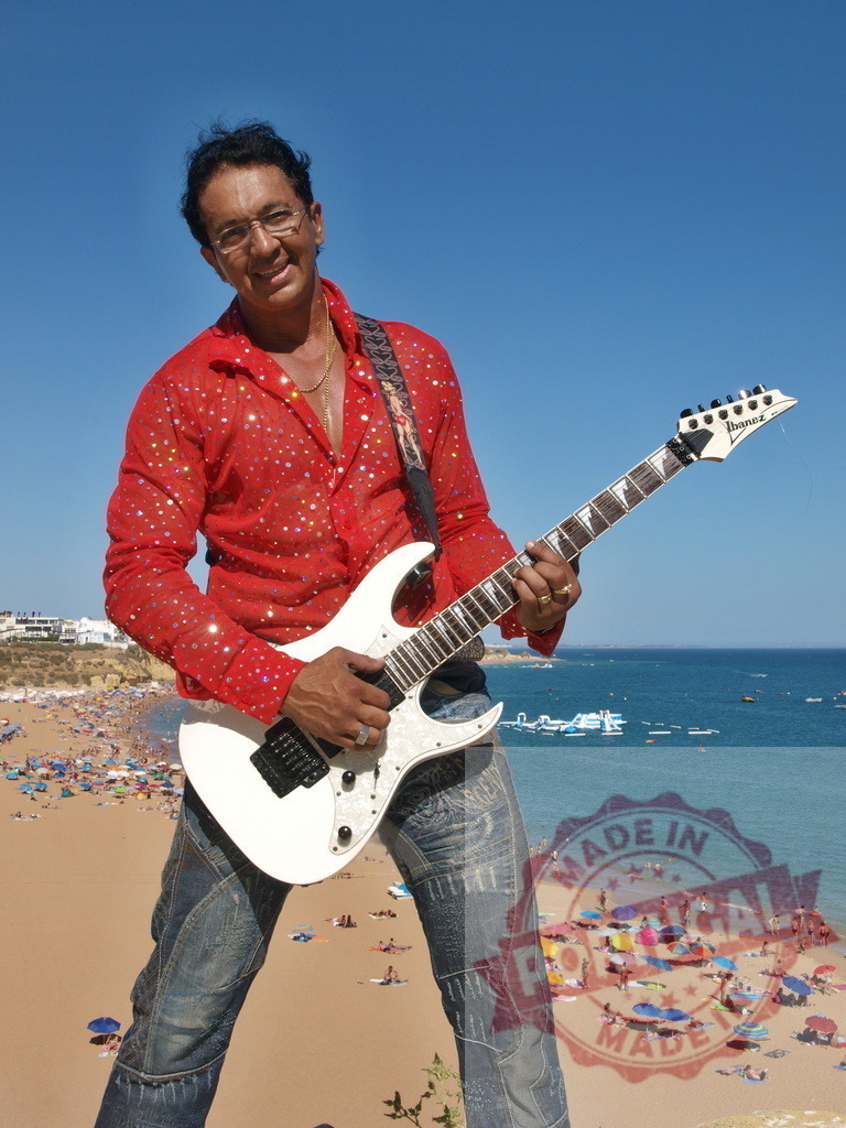 Musician playing electric guitar on a cliff overlooking the beach | Guitarist playing electric guitar on a cliff overlooking a crowded beach in the Algarve region of Portugal - Realisiert mit Pictrs.com