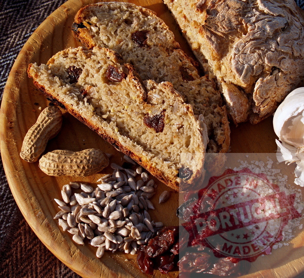 Artisan bread slices with wholesome ingredients on wood | Artisan bread slices, sunflower seeds, peanuts, raisins, garlic, and salt on a wooden board - Realisiert mit Pictrs.com