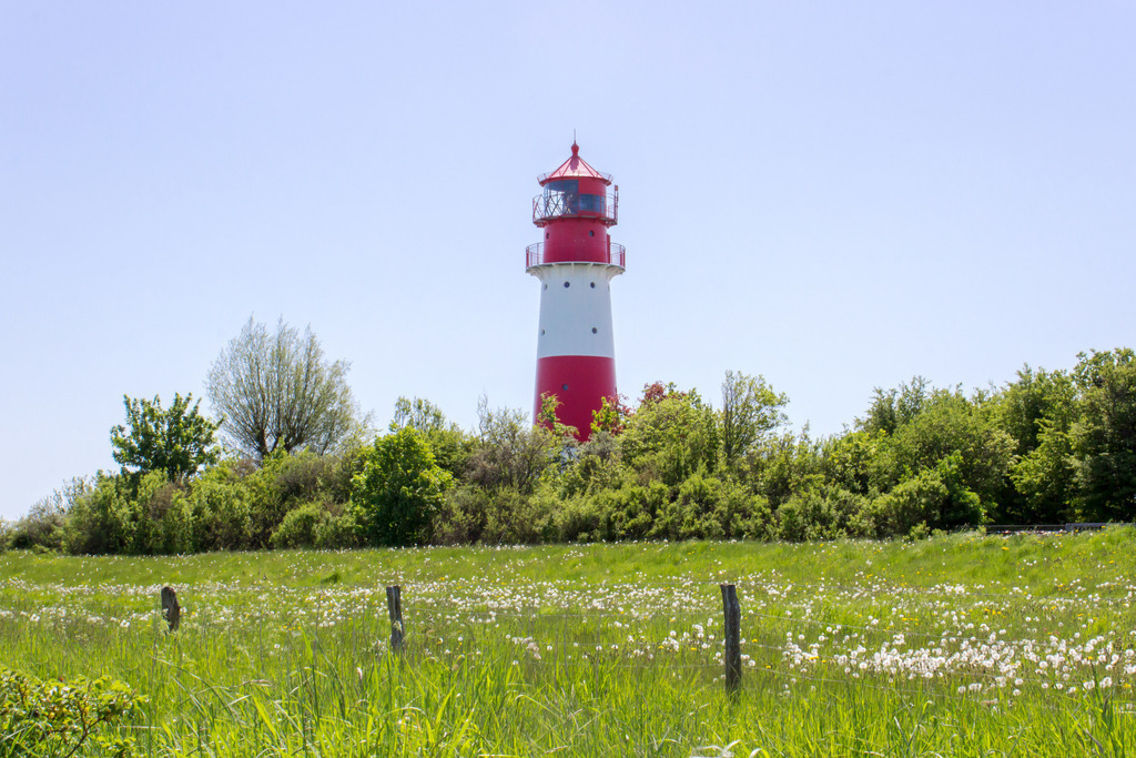 Wandbild: Leuchtturm in Falshöft im Frühling | Dieses Wandbild im Querformat zeigt einen der schönsten Leuchttürme an der Ostseeküste in Falshöft. Im Vordergrund befindet sich eine grüne Wiese und direkt vor dem Leuchtturm befinden sich zahlreiche Bäume. Holen Sie sich dieses idyllische Wandbild nach Hause in Ihr Wohnzimmer, Küche, Schlafzimmer oder in Ihre Ferienwohnung, Büro, den Arbeitsplatz oder Ihre Praxis. Es ist als Leinwand, als Acrylglas/Glasbild und Aluminium-Platte in vielen Abmessungen erhältlich. - Realisiert mit Pictrs.com