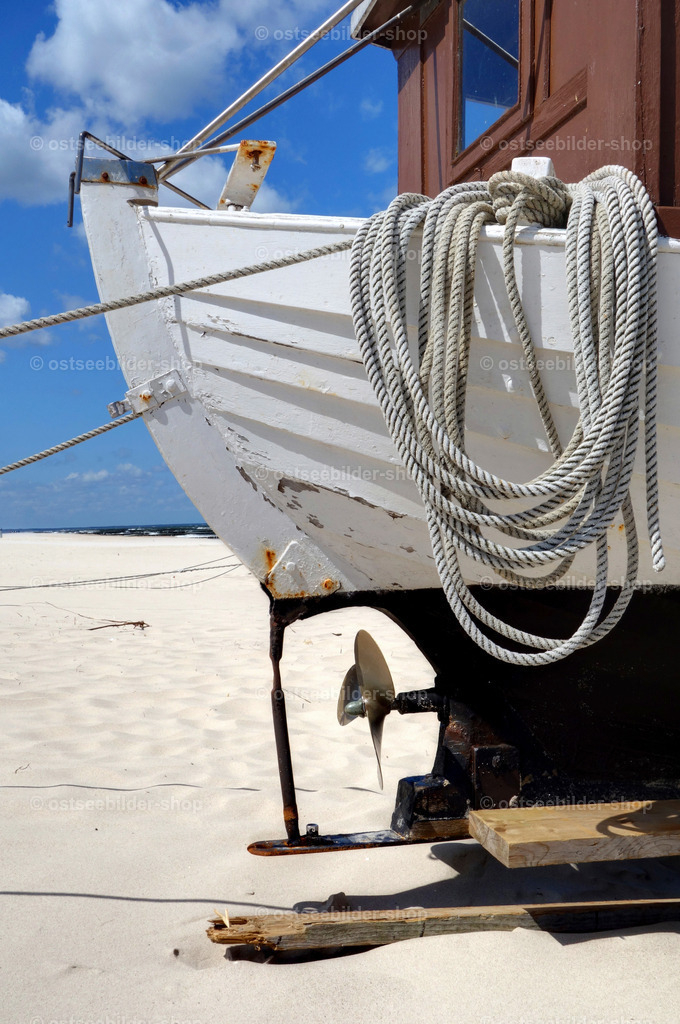 Am Ostseestrand liegendes Fischerboot | Am Ostseestrand von Koserow liegt ein Fischerboot im Sand mit aufgewickeltem Tauwerk über der Bordwand.