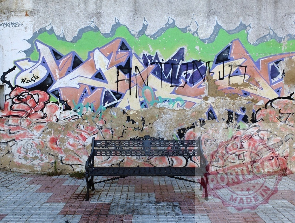 Urban art wall with empty black bench | Empty black bench standing against a colorful urban graffiti wall with rose artwork - Realized with Pictrs.com