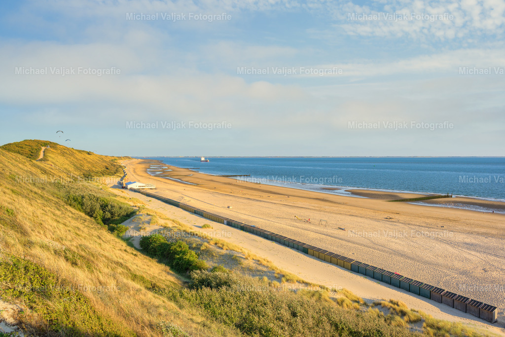 Blick von den Dünen über den Strand bei Zoutelande | Von den Dünen aus eröffnet sich ein weiter Blick über den Strand von Zoutelande und die Nordsee. Der sanft geschwungene Küstenverlauf, der breite Sandstrand und das endlose Meer vermitteln die typische Weite und Ruhe der zeeländischen Küstenlandschaft.Die Dünen im Vordergrund geben dem Motiv Tiefe und führen den Blick entlang der Küste hinaus zum Horizont. Ein zeitloses Landschaftsfoto von Zoutelande in Zeeland, Niederlande, das die natürliche Schönheit und besondere Atmosphäre der niederländischen Nordseeküste einfängt. - Realisiert mit Pictrs.com