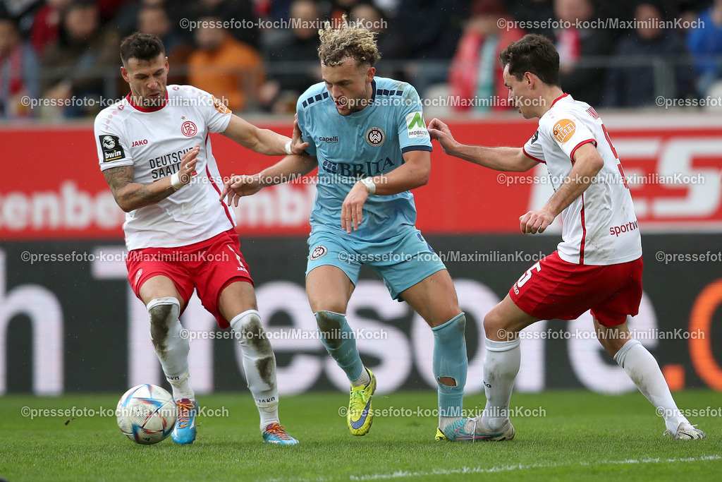 RWE3Liga25032301040 | 25.03.2023, Essen, Fußball, bwin 3.Liga Fußball Herren, Stadion an der Hafenstraße, 29. Spieltag, Saison 2022 2023, Rot-Weiss Essen – SV Wehen Wiesbaden: Benedict Hollerbach von SV Wehen Wiesbaden gegen Andreas Wiegel und Clemens Fandrich von Rot-Weiss Essen . DFB regulations prohibit any use of photographs as image sequences and or quasi-video.