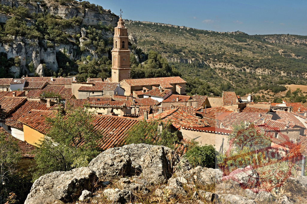 Spanish village with bell tower in rural mountain landscape | Rural village in Spain with traditional terracotta roofs and a church bell tower against mountains - Realisiert mit Pictrs.com