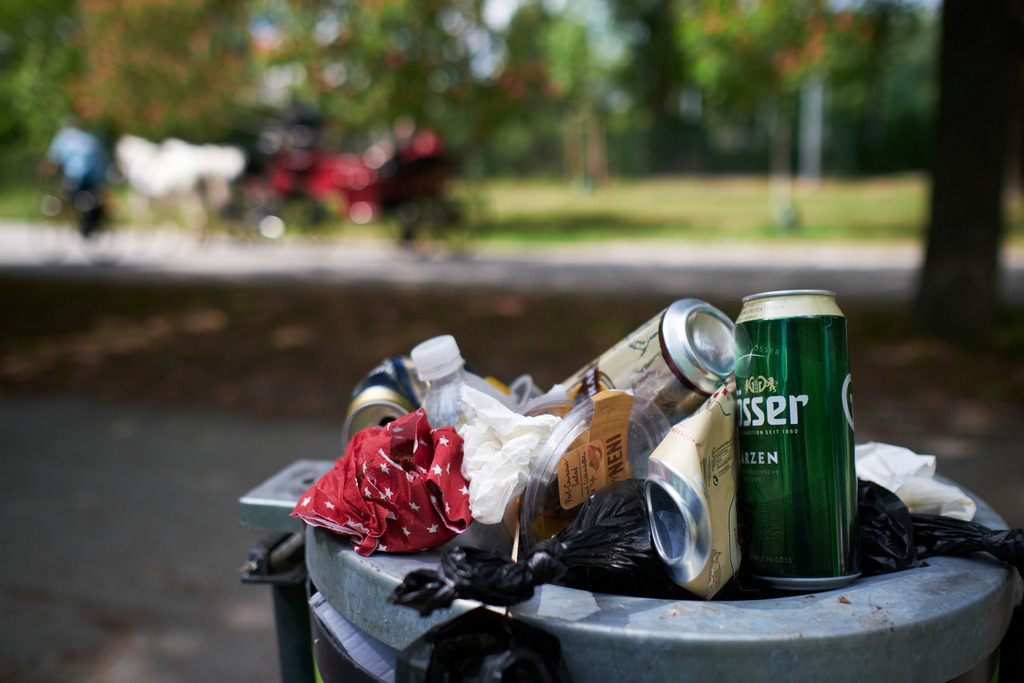 überfüllter Abfalleimer im Pratergelände | Wien, Austria - May 01, 2020: überfüllter Abfalleimer im Pratergelände, im Hintergrund ein Fiaker. - Realisiert mit Pictrs.com