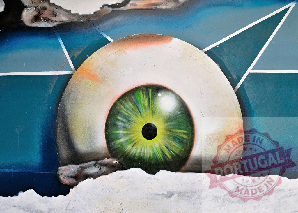 Large green eye watching from colorful graffiti wall | Urban art depicting a large eye looking out from a graffiti wall, creating a surreal and captivating scene - Realized with Pictrs.com