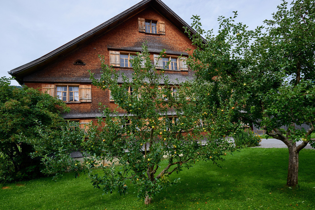 Heimatmuseum Bezau | Bezau, Austria - July 27, 2017: Heimatmuseum Bezau, Seitenansicht des geschindelten Bauernhauses mit Obstgarten. - Realisiert mit Pictrs.com