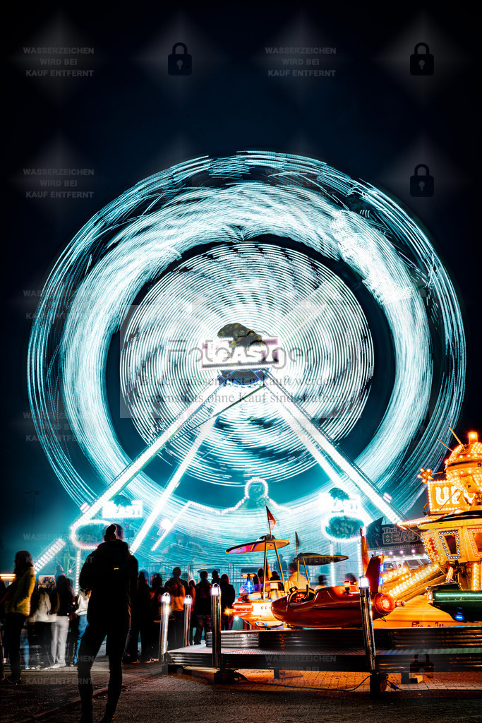 The Beast – Licht und Bewegung | Ein Fahrgeschäft, das seinem Namen alle Ehre macht: „The Beast“ leuchtet in intensiven Blautönen und zieht mit seiner Bewegung spiralförmige Lichtspuren in den Nachthimmel.Dieses Foto fängt die Faszination und Energie eines Jahrmarktabsends perfekt ein – voller Leben, Farbe und Bewegung. - Realisiert mit Pictrs.com